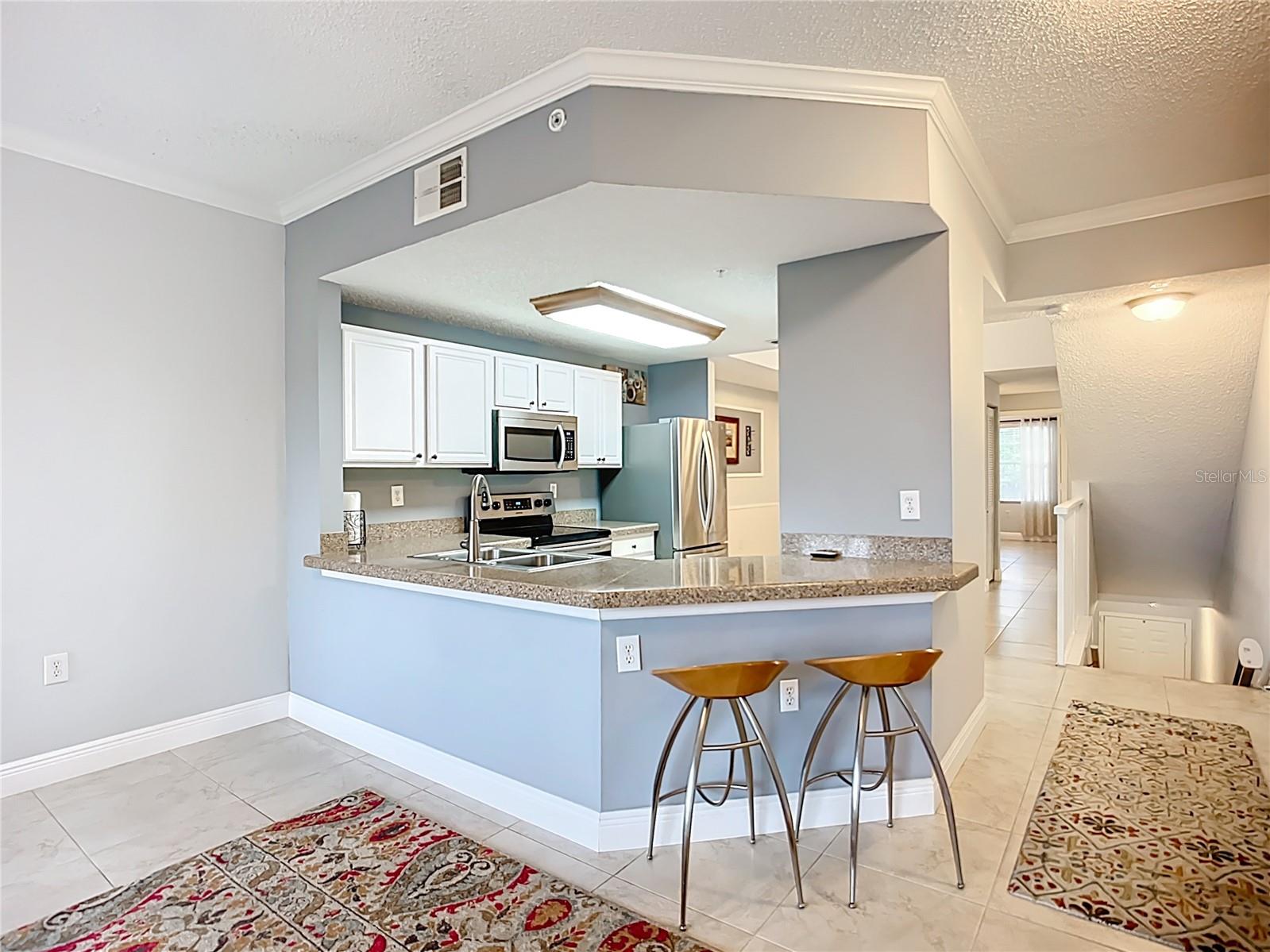 View from living room into kitchen, stairway down to garage and entry shown at right.