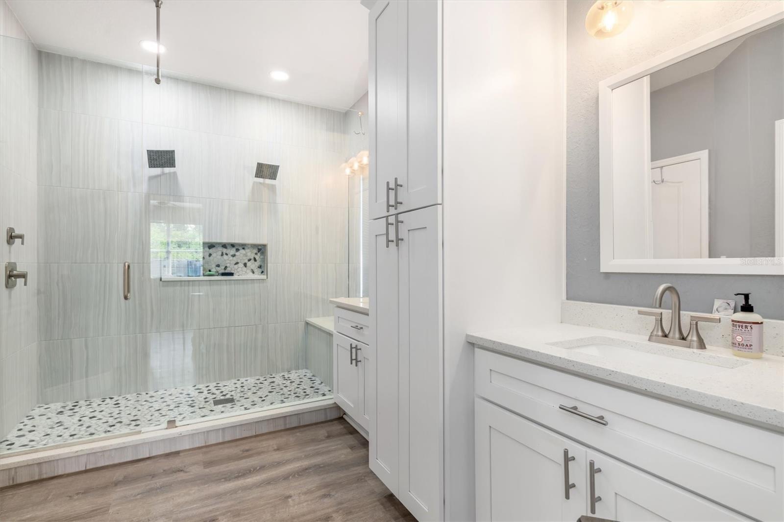 Upgraded primary bathroom with white cabinets and storage tower.