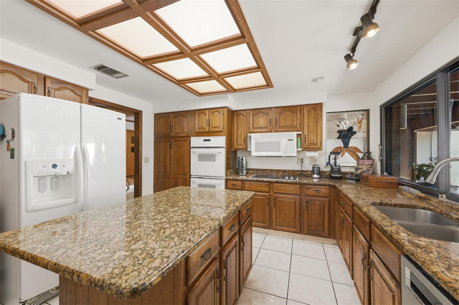 Kitchen with Double Ovens, Granite Counters and Wall of Windows Overlooking Pool & Gardens