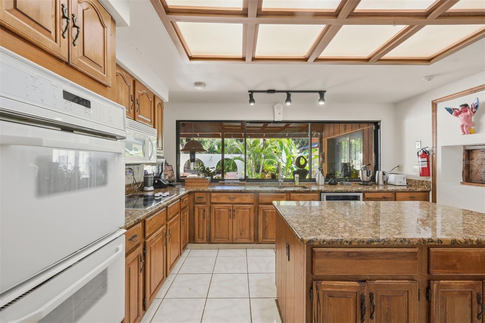 Kitchen with Double Ovens, Granite Counters and Wall of Windows Overlooking Pool & Gardens