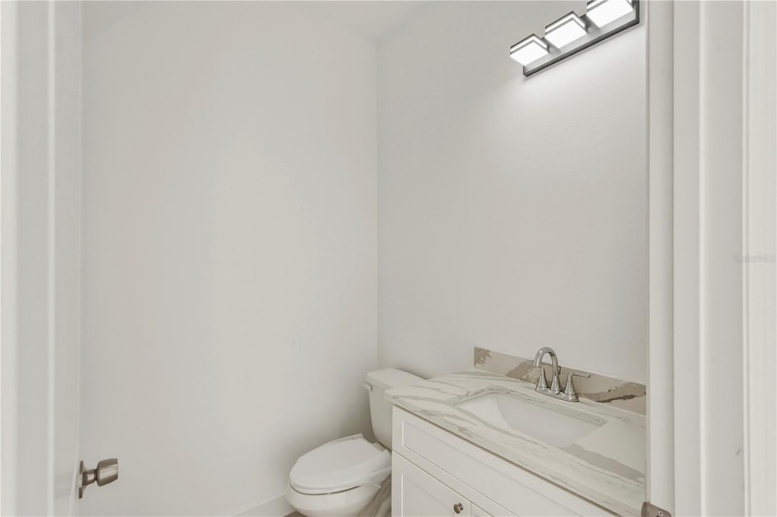 Convenient Half Bath with Quartz Vanity.