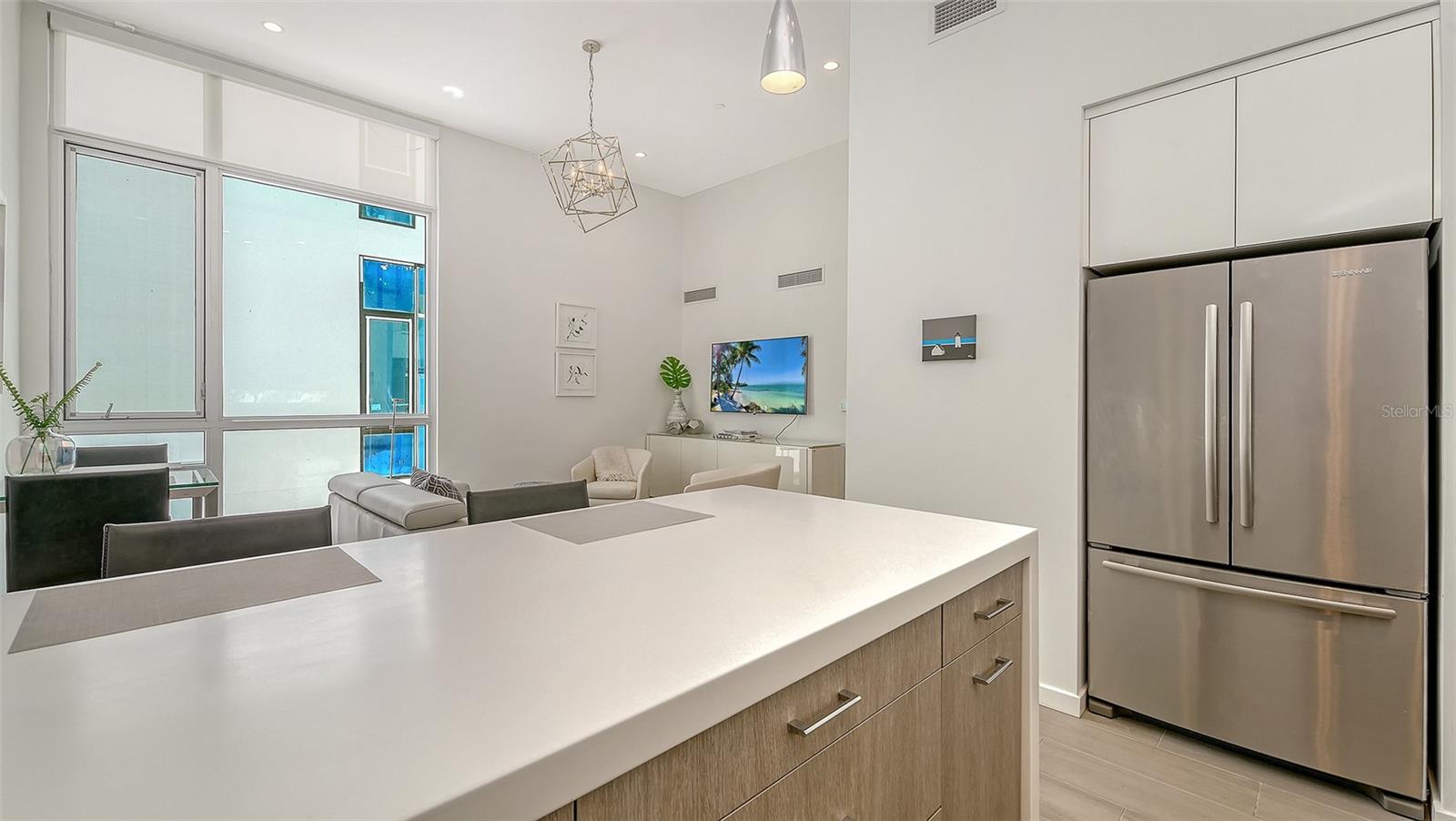 Contemporary kitchen with solid surface countertops and waterfall-edge island and SS appliances, including Miele induction range & Miele d/w, hood, and oven/microwave.