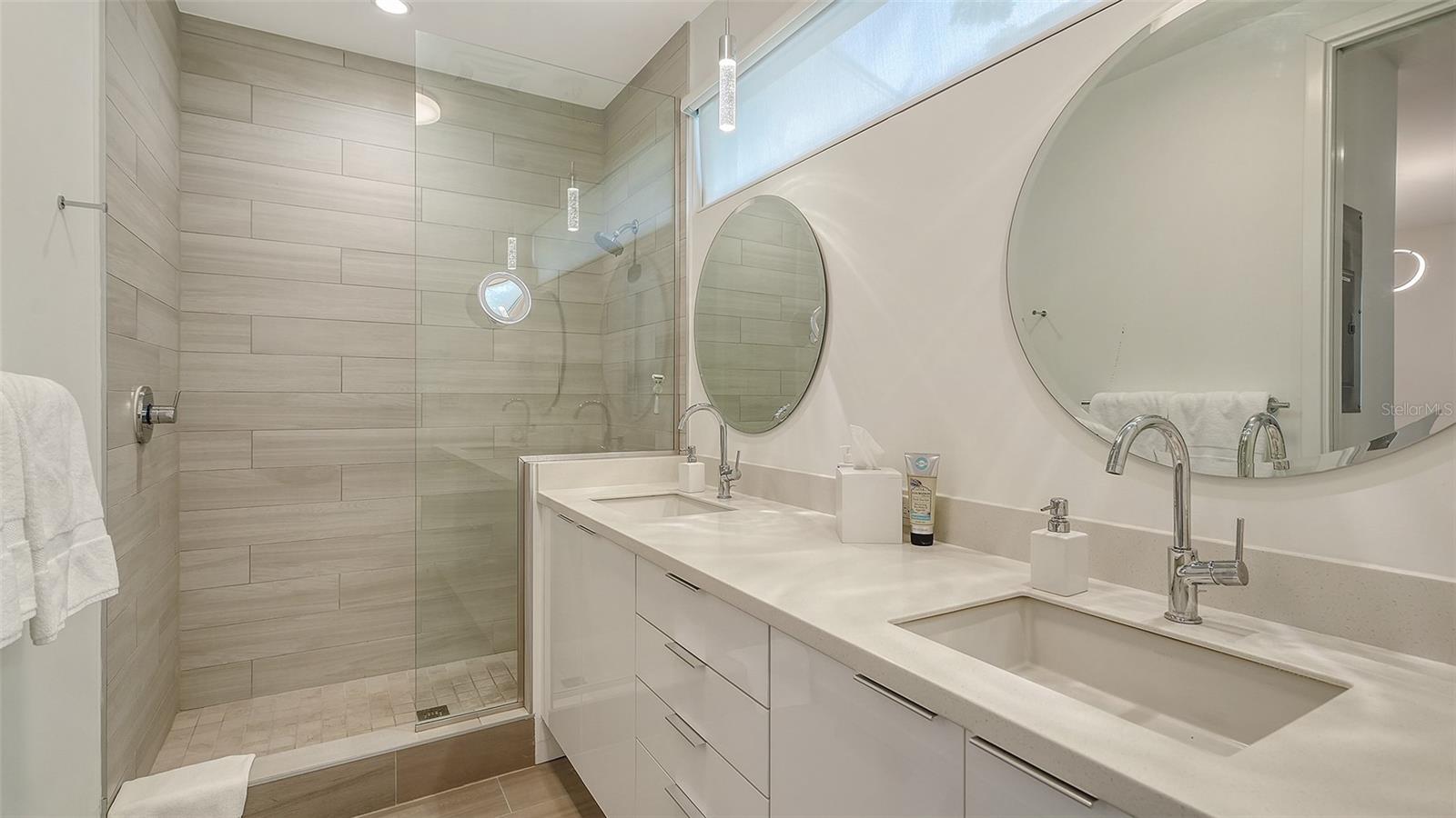Roomy modern  bathroom with dual sinks and private toilet room.