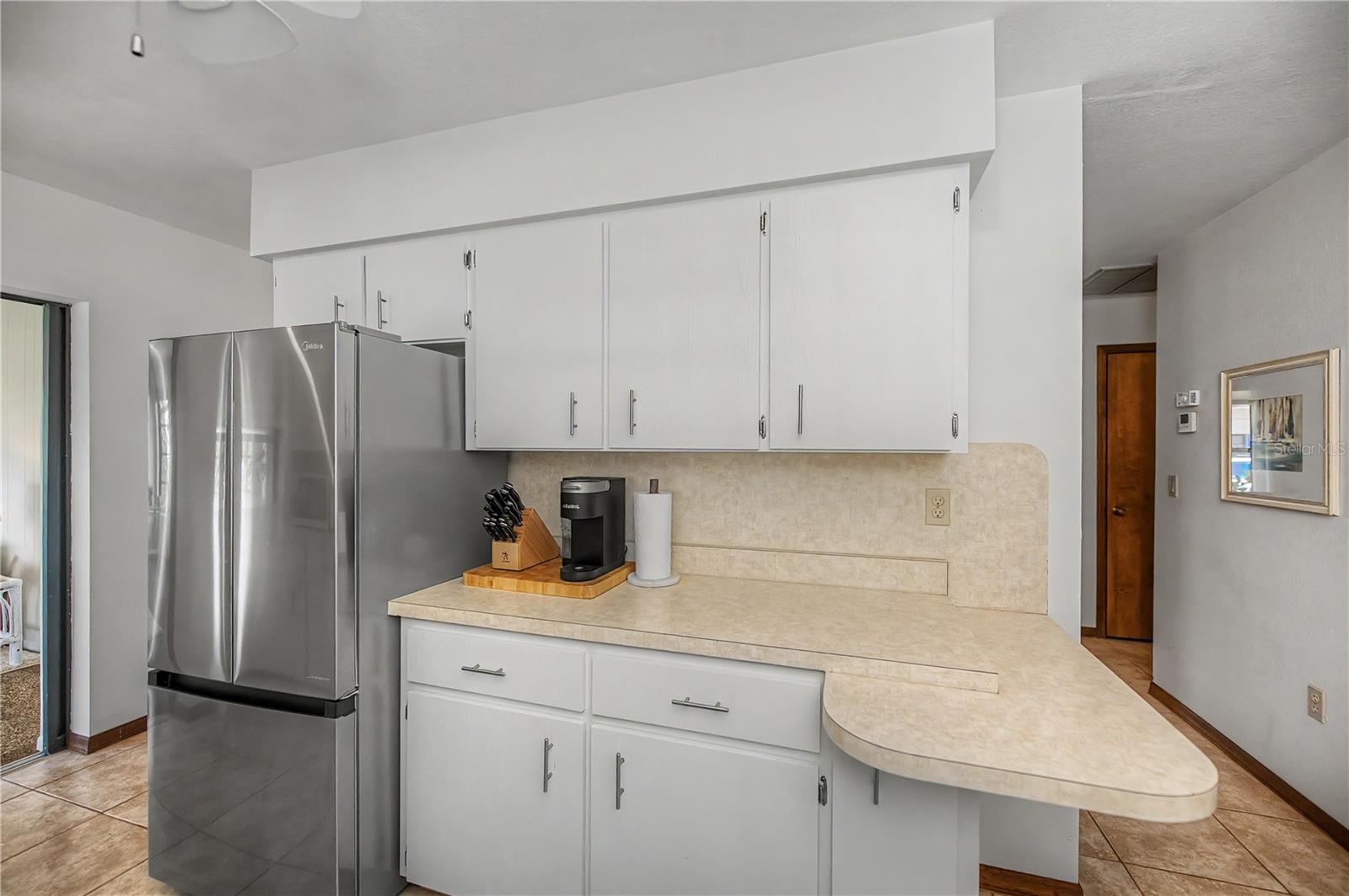 Kitchen Breakfast Bar with Additional Prep Space and Stainless Steel Refrigerator.