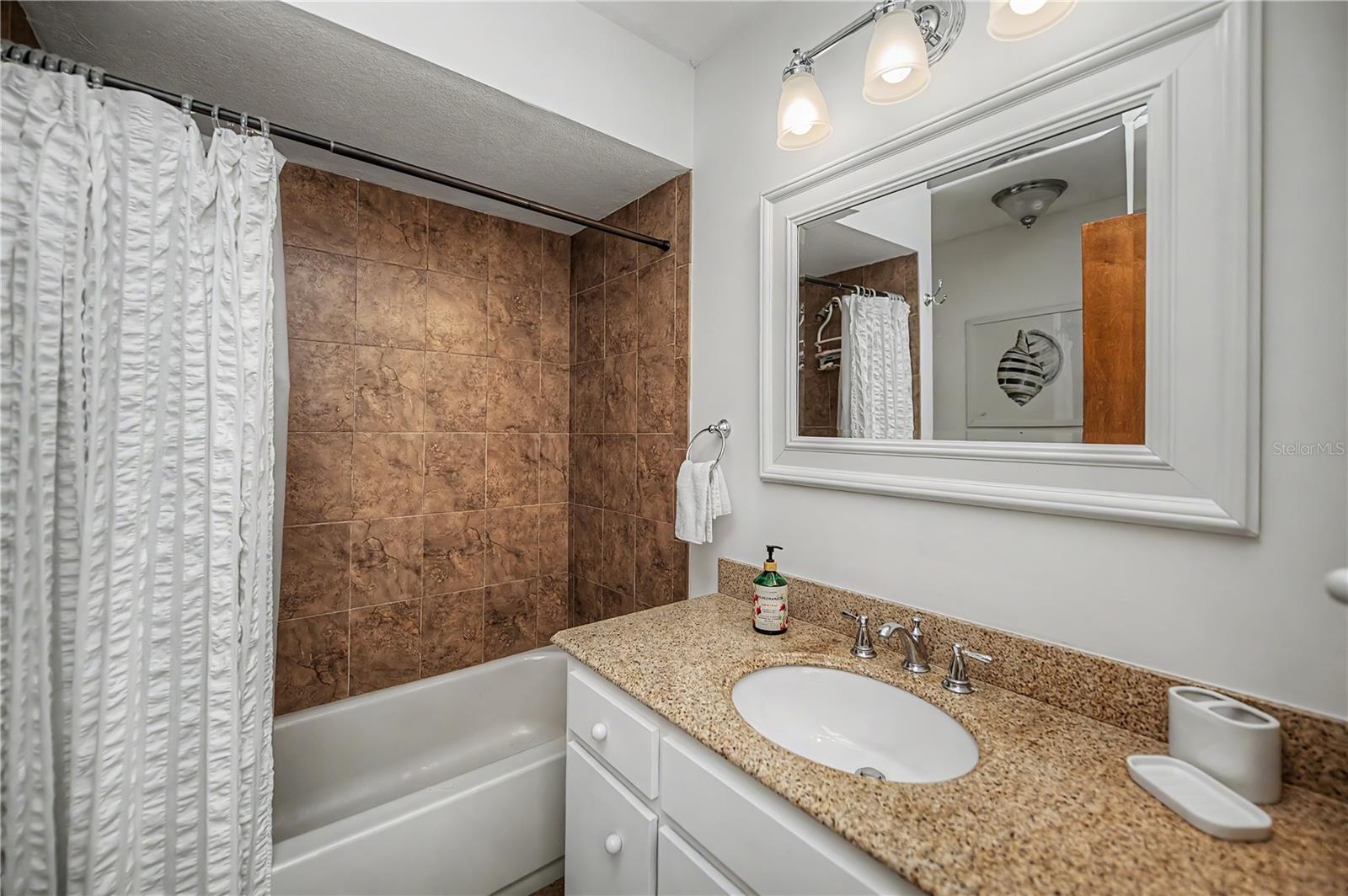Guest Bathroom with Granite Vanity and Tiled Tub/Shower Combo.