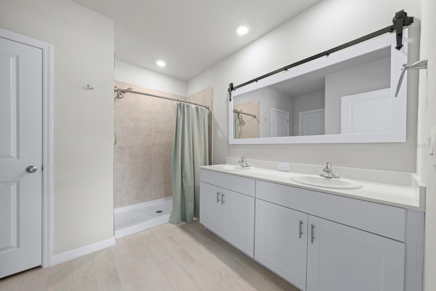 Primary bathroom with walk-in shower, two sinks, and linen closet.