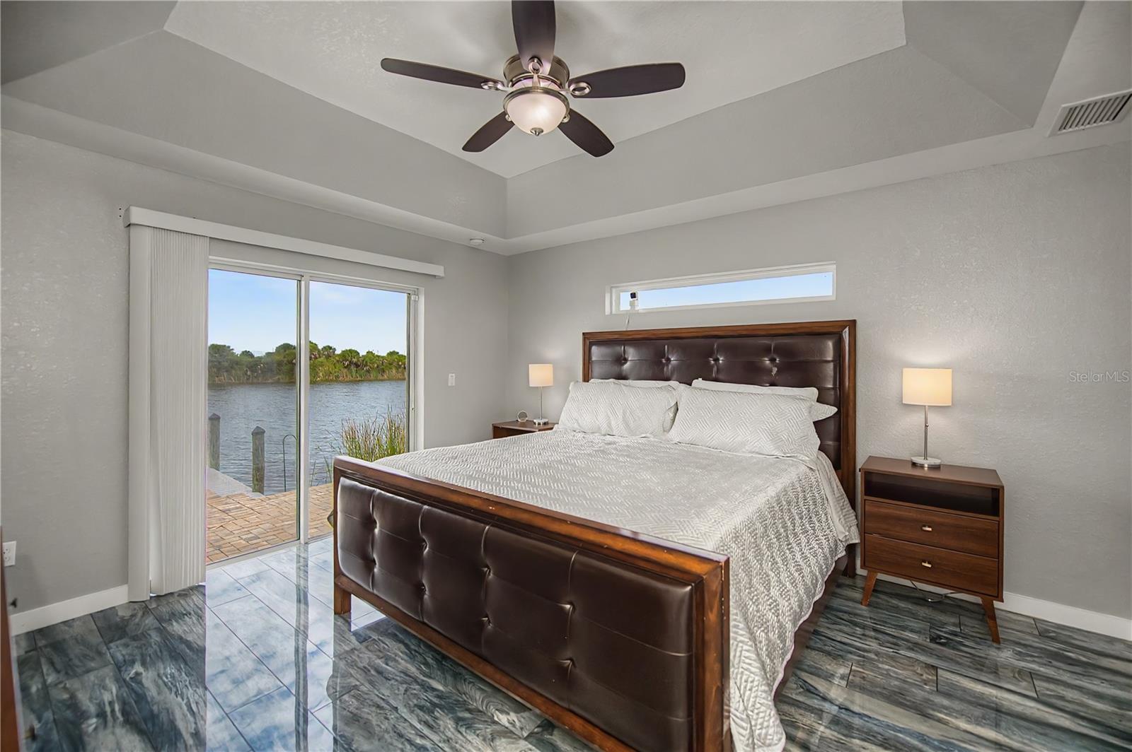 Waterfront Primary Suite with Private Patio Access, Tray Ceilings, and Tranquil Canal Views.