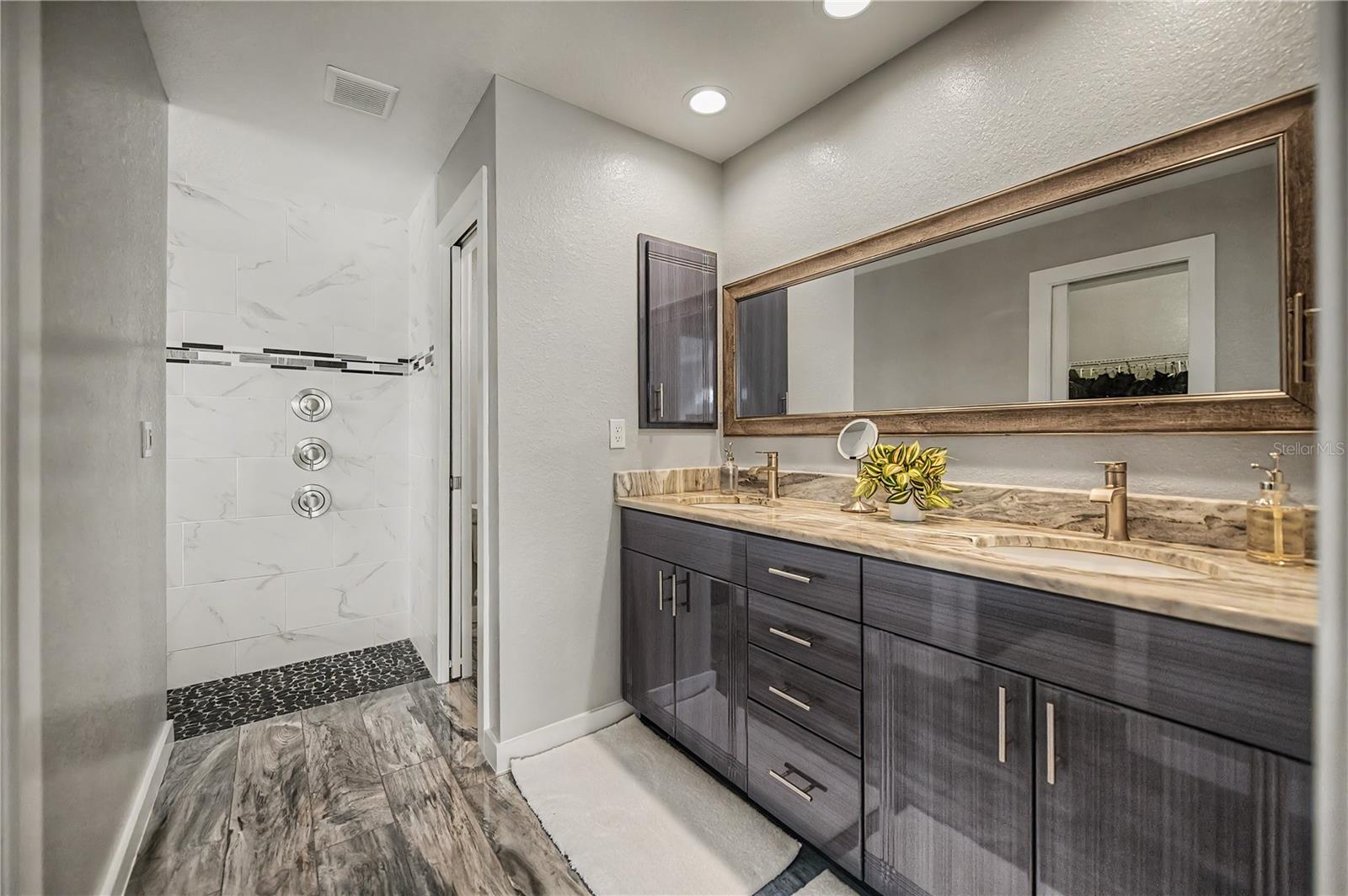 Primary Ensuite Featuring Dual Vanities, Designer Finishes, and a Spa-Style Walk-In Shower.