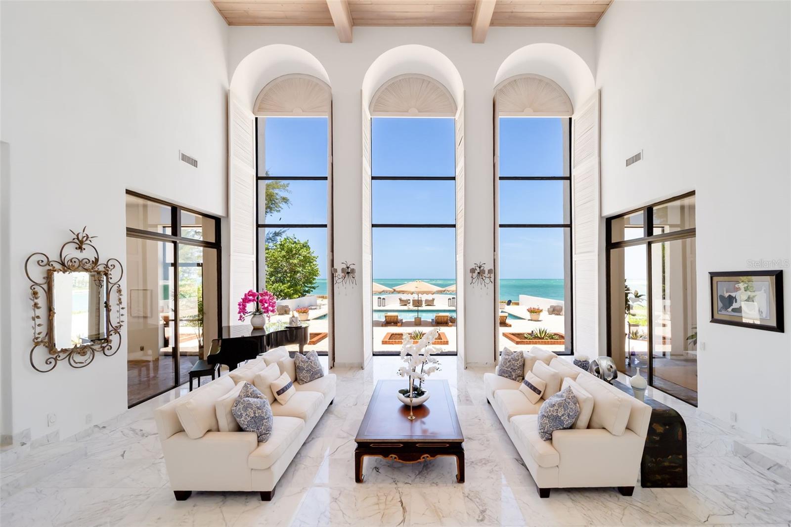From here the gathering room opens up to the outdoors onto covered and screened terraces overlooking western sunsets.  There are two wet bars in this room and the formal living and formal dining rooms off to either side.