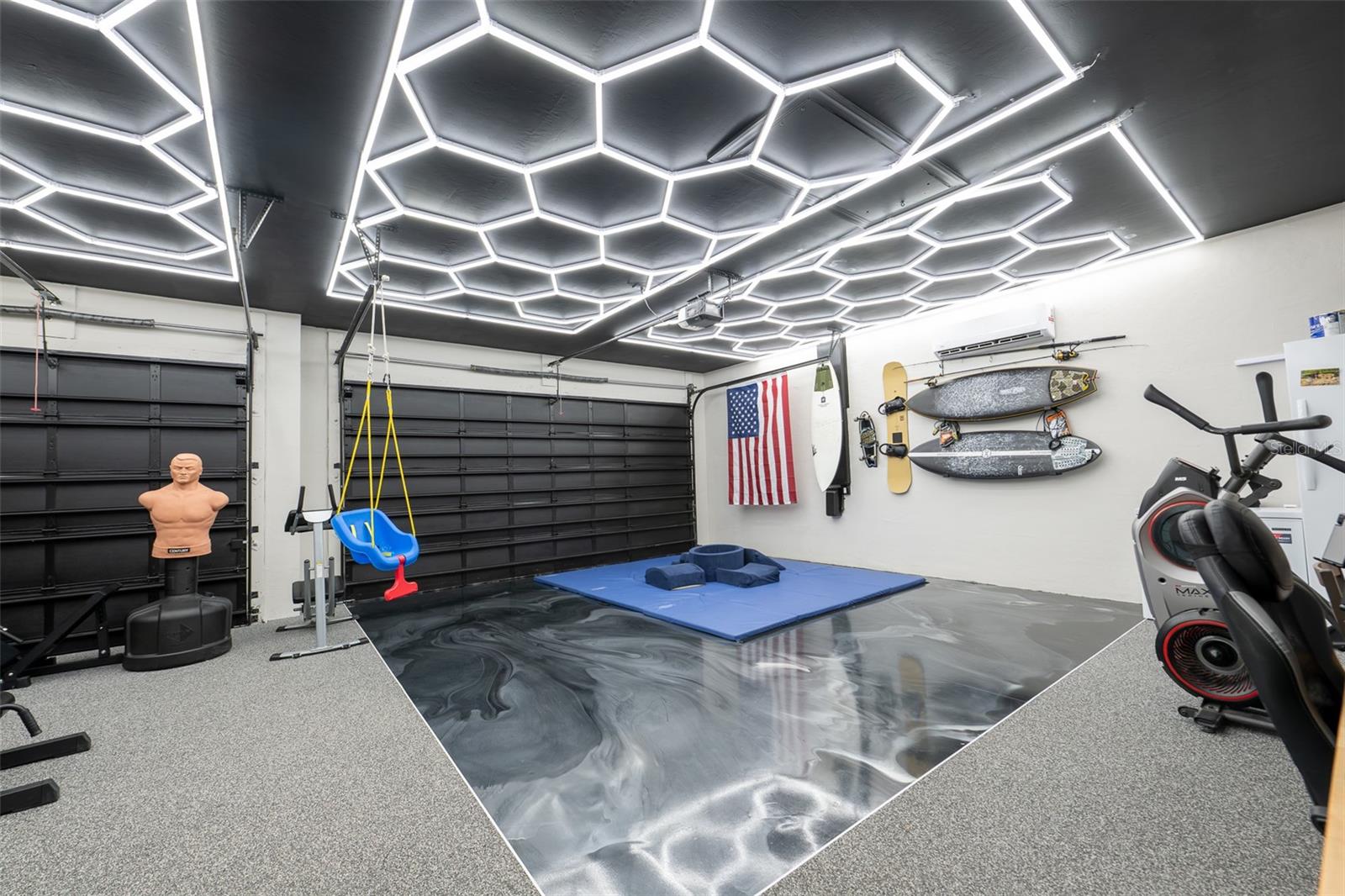 Prepare to be amazed! The attached multi-car garage has been meticulously transformed into a world-class home gym and recreation center. It features a jaw-dropping custom hexagon LED grid ceiling lighting system, a dedicated mini-split AC system for perfect climate control, and insulated black garage doors.