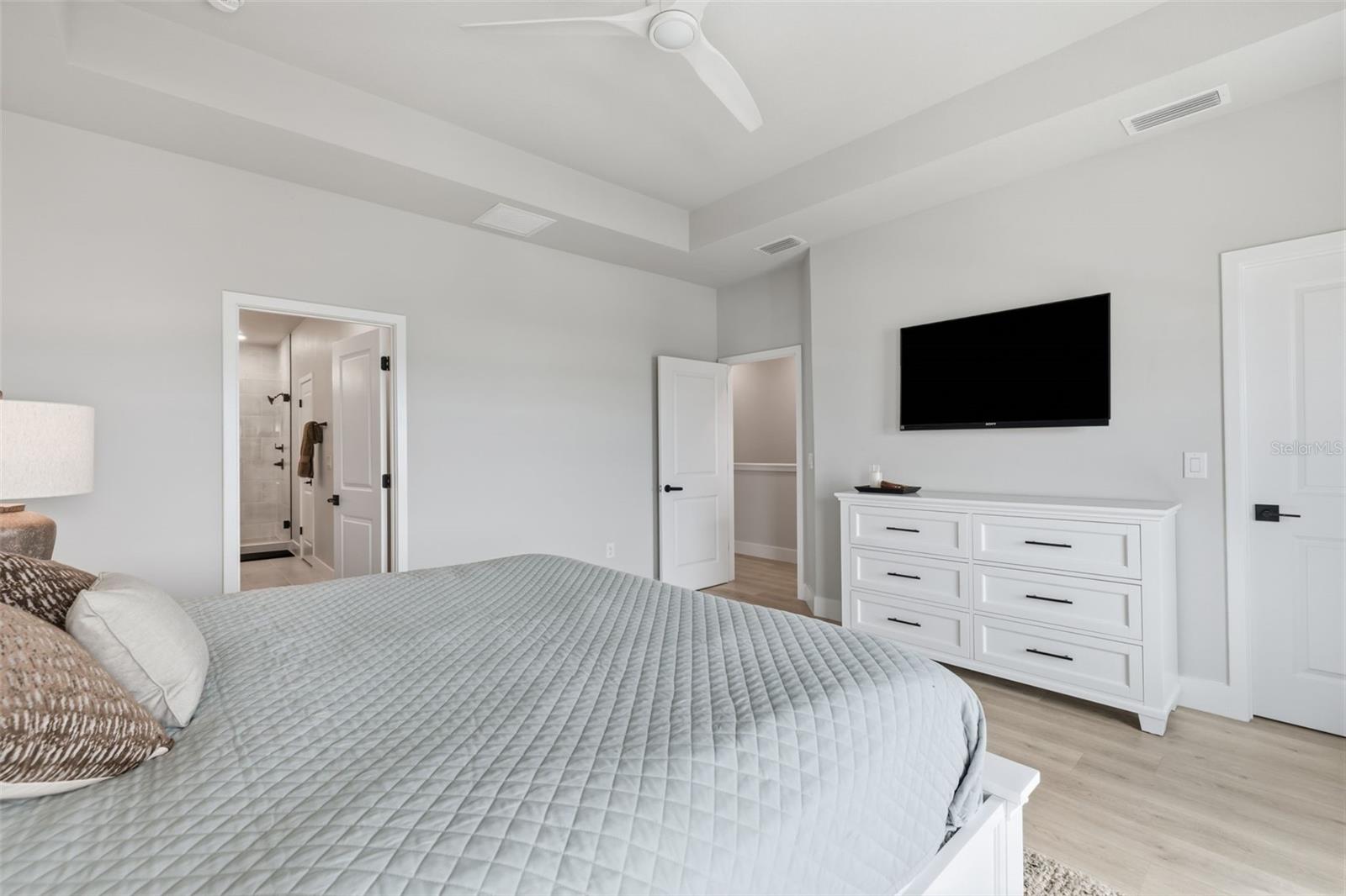 Primary bedroom with trey ceilings and double walk-in closets