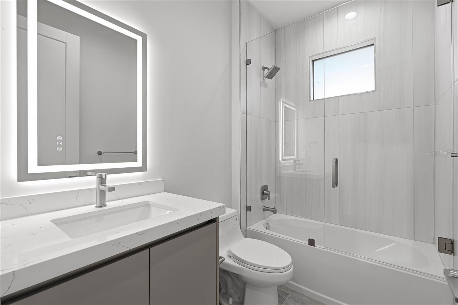 Guest Bathroom with Quartz Vanity and Tub/Shower Combo with Glass Enclosure