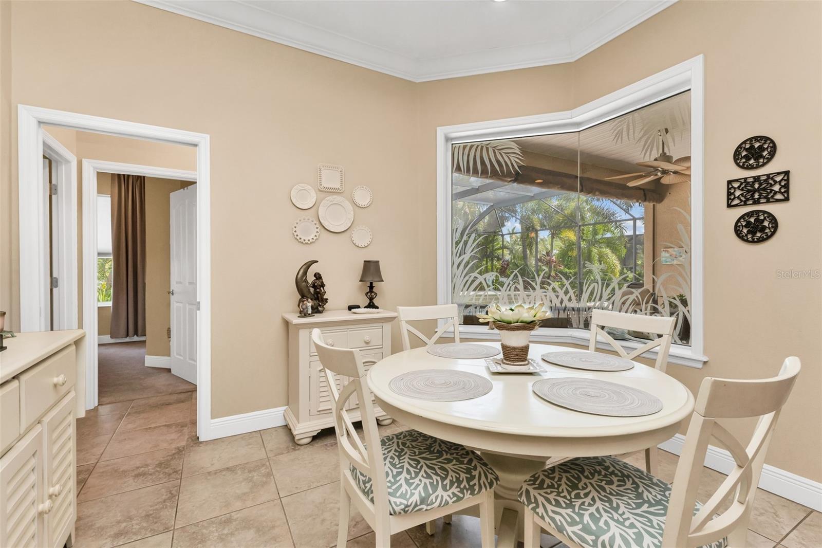 Dining with elegant, mitered window overlooking the pool area