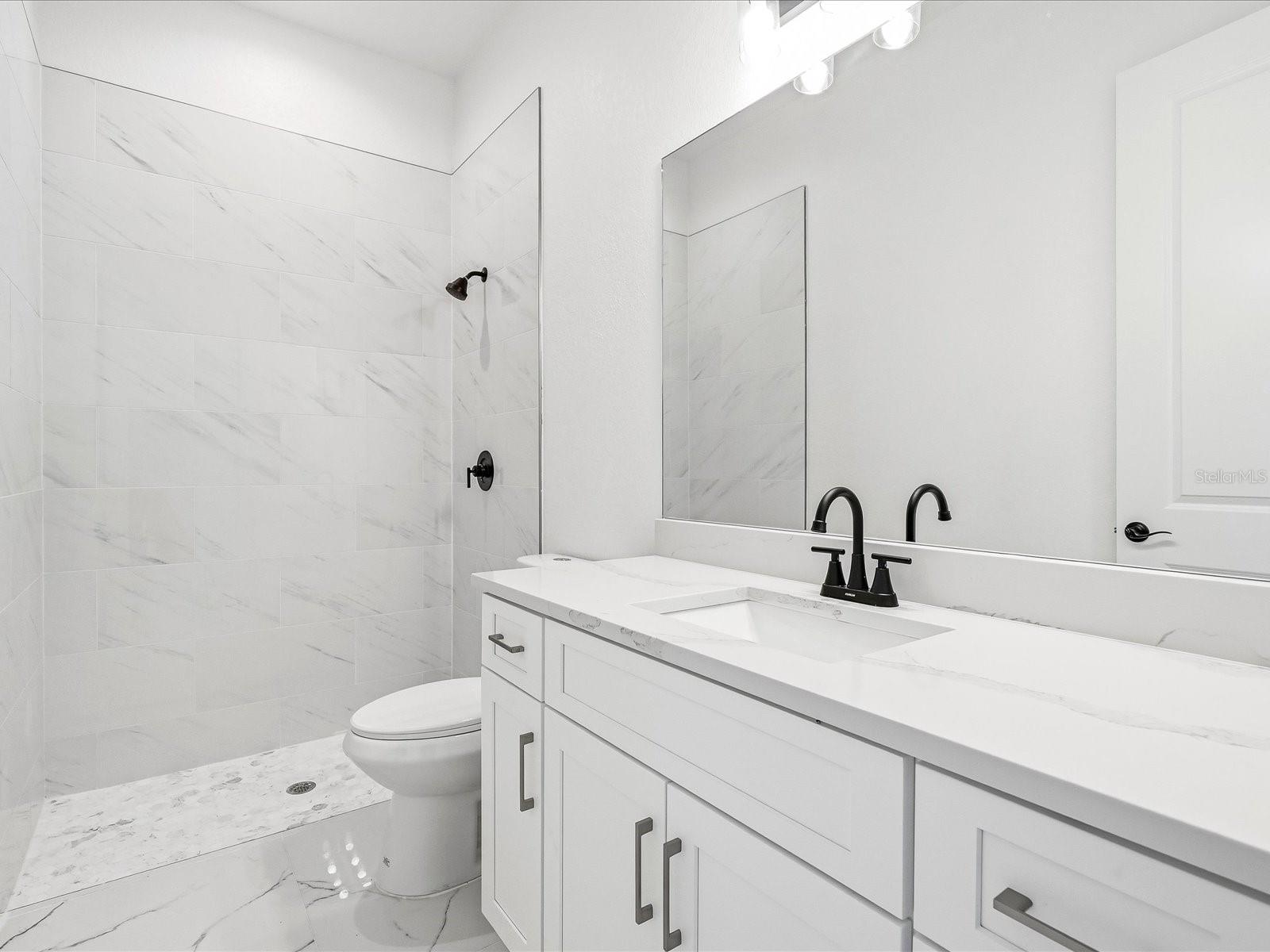 Guest Bathroom with fully tiled shower & quartz countertops