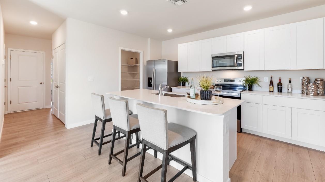 Inside of the kitchen. Stainless steel appliances, quartz countertops, walk-in corner pantry