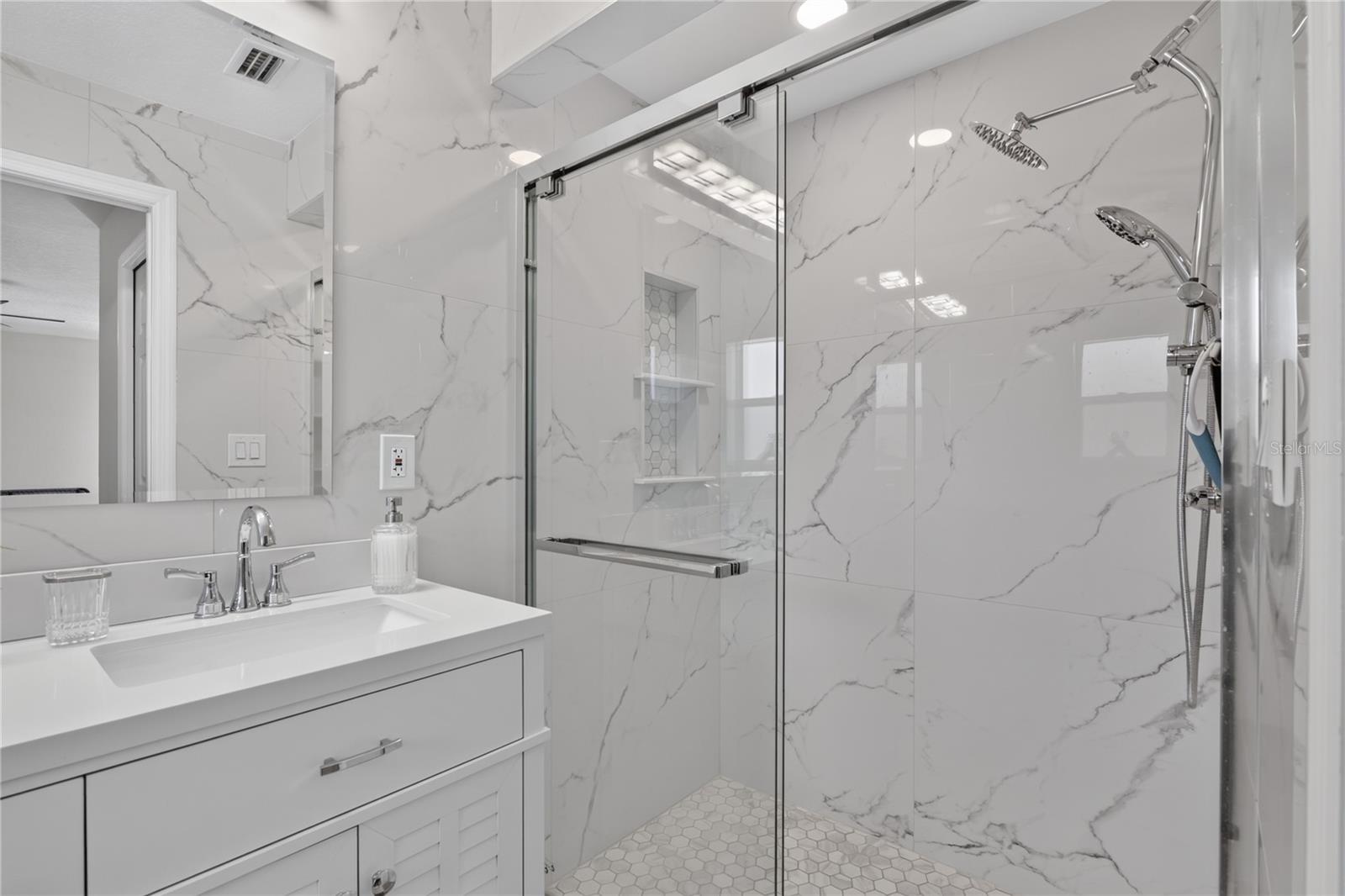 Primary bathroom with double sinks and glass shower doors.