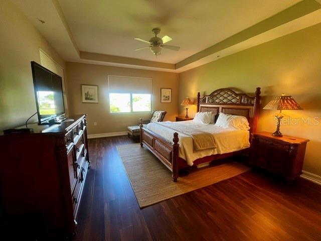 Primary bedroom with tray ceilings, luxury vinyl flooring, and electric window coverings