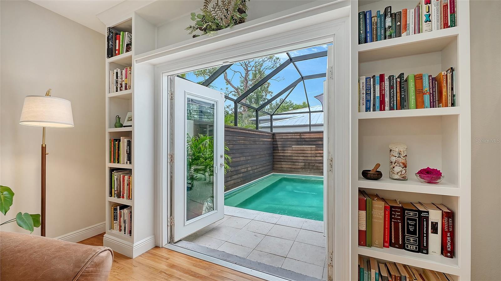 Custom French doors provide a beautiful visual connection from the interior living space to the private heated pool and screened courtyard.