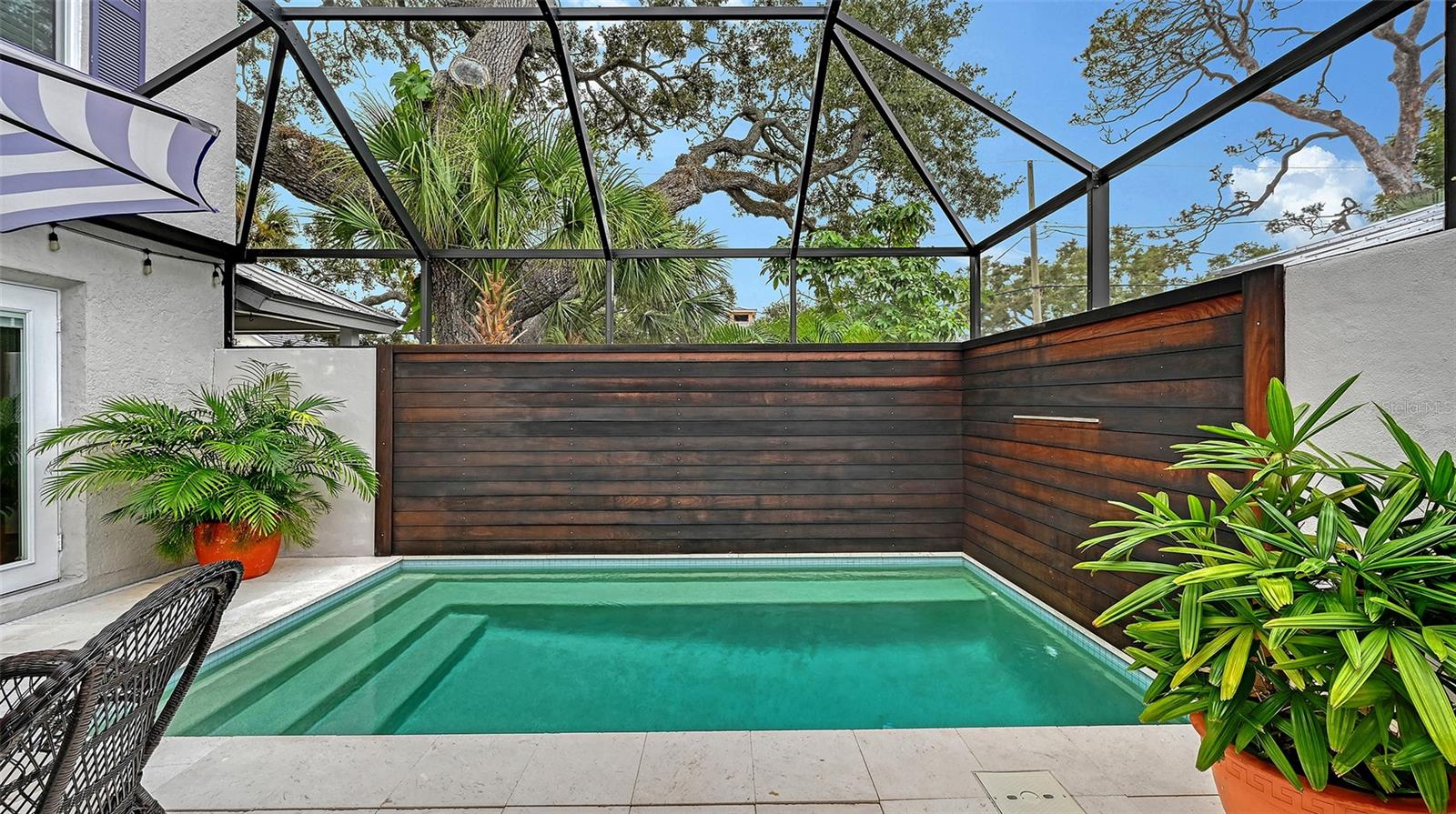 Private screened pool retreat creates an elevated resort-style setting surrounded by lush tropical landscaping and custom wood privacy fencing.