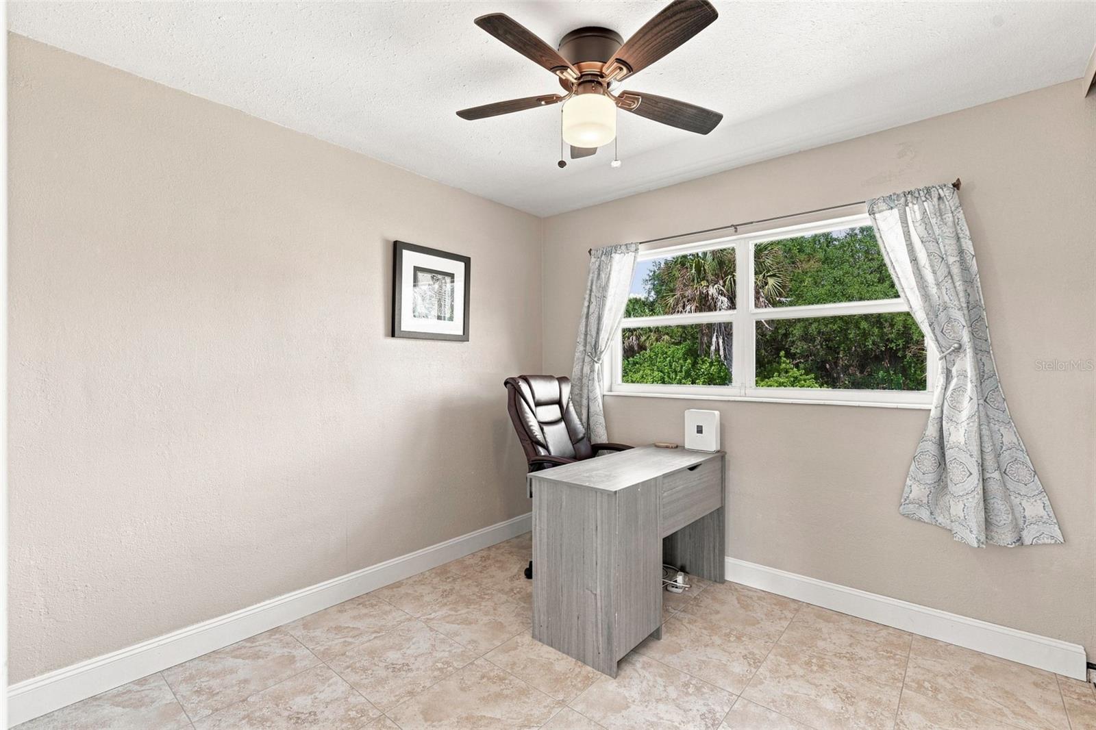 Second Bedroom with Large Window, Ceiling Fan, & Tile Floor