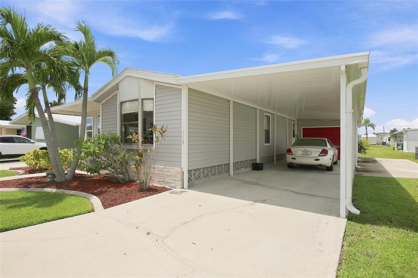 Parking under carport with garage and stairway entrance into home
